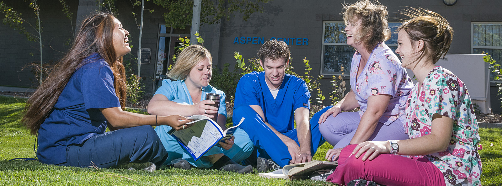 Healthcare students sitting on campus lawn