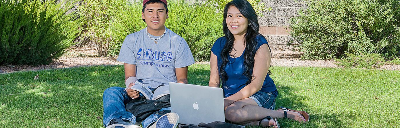 two high school students sitting on NPC lawn with laptop