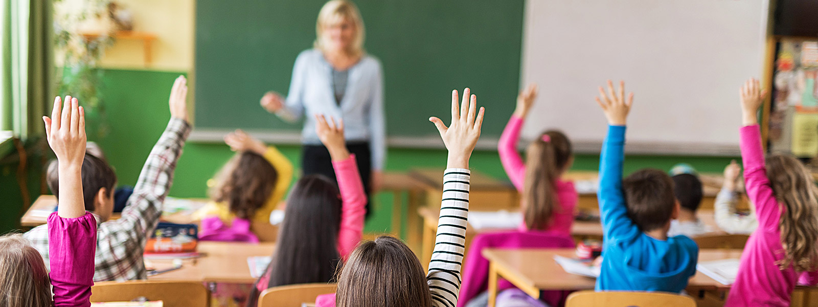 students in classroom raising their hands to answer question