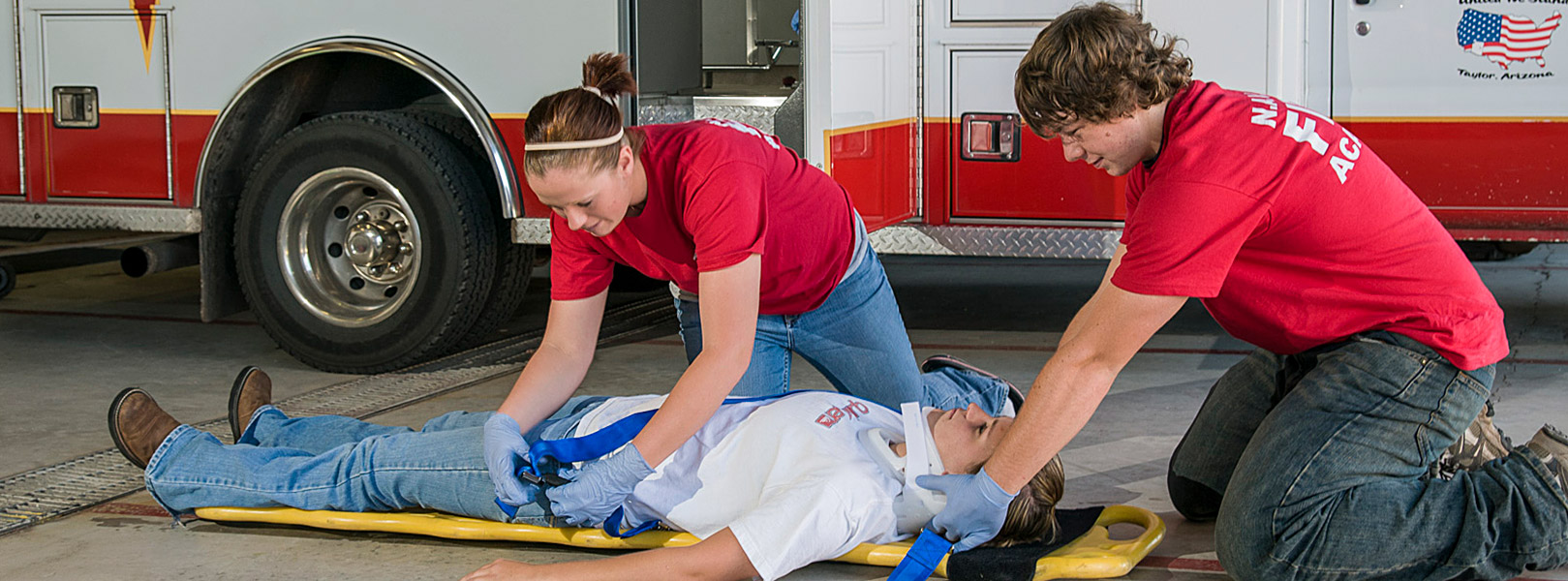 two students strapping a patient to a body board