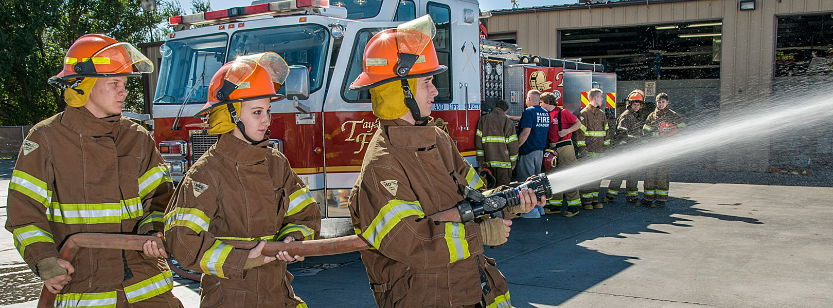 three students spraying fire hose