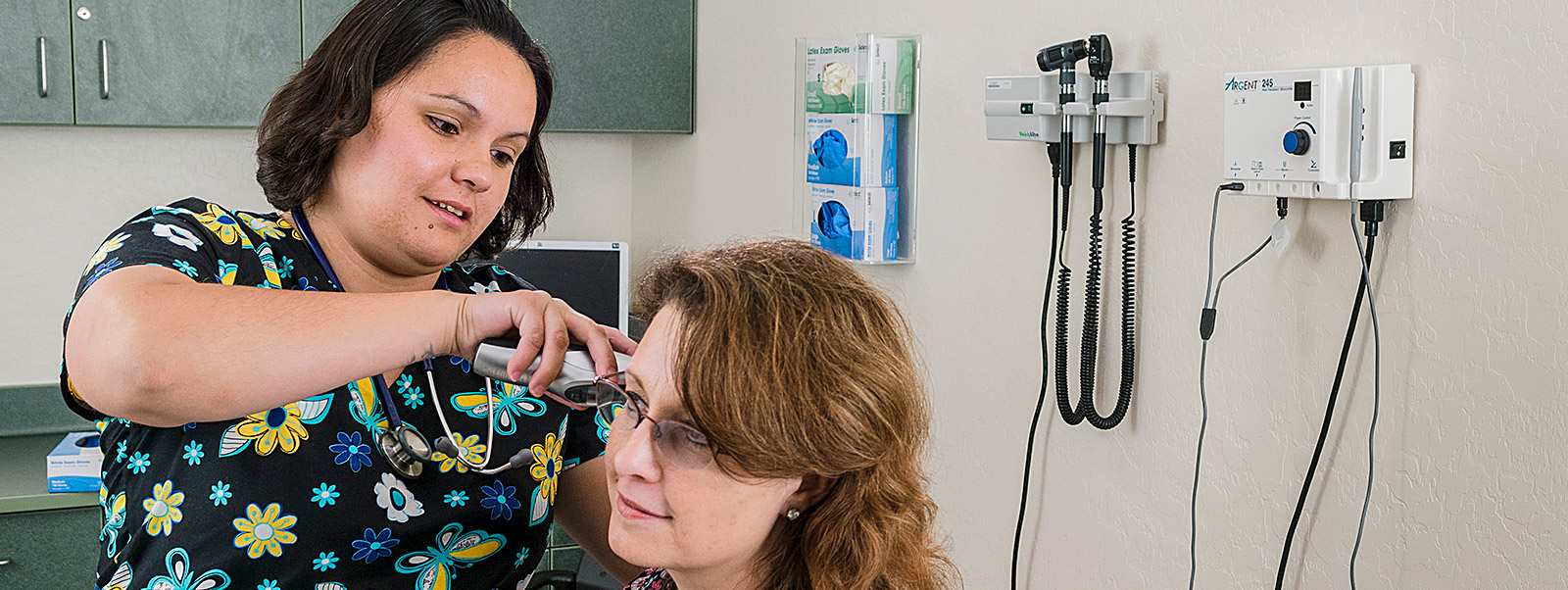 student interning in doctor's office checks patient temperature