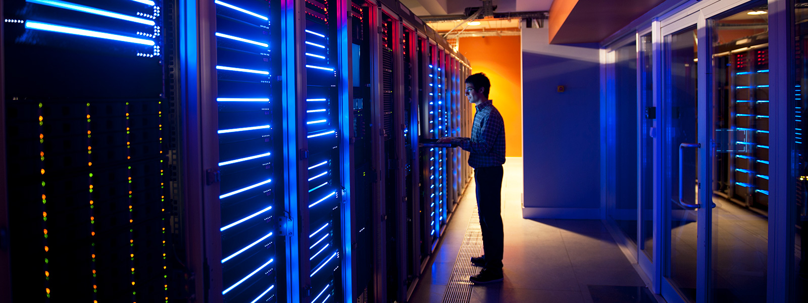 man on laptop working in server room