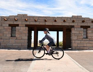 Cyclist pedaling past an old structure