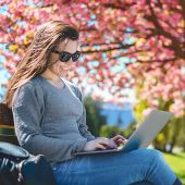 Girl sitting on bench looking at laptop