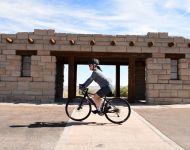 Cyclist pedaling past an old structure