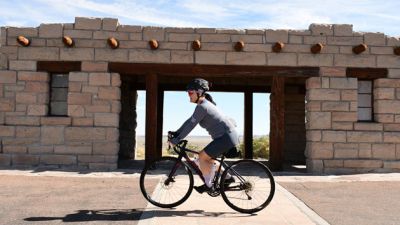 Cyclist pedaling past an old structure